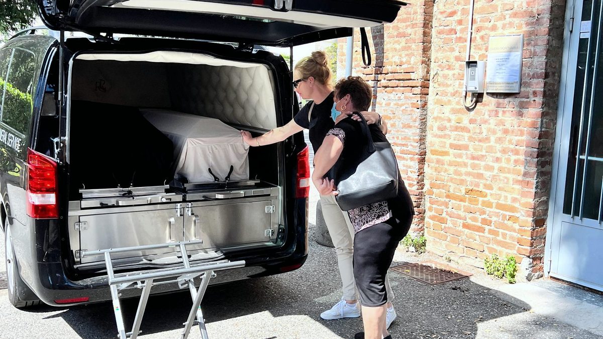 Працівники ритуальної служби завантажують тіло померлого до спеціалізованого мікроавтобуса за кордоном