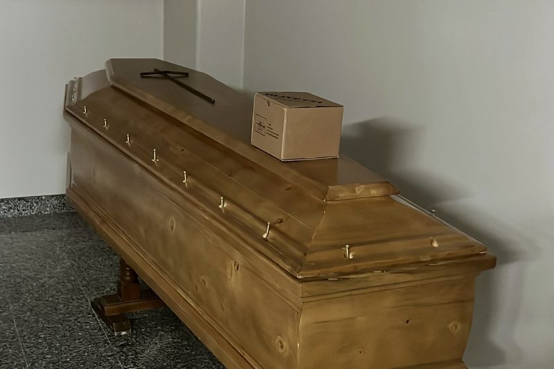 Дерев'яна труна з транспортувальною капсулою в залі ритуальної служби